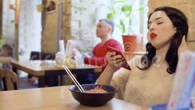 美丽的黑发女人在手机上拍<strong>韩国菜</strong>